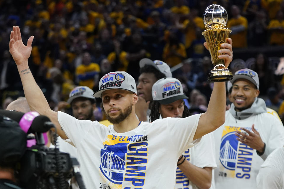 Golden State Warriors' Stephen Curry holds up the conference finals MVP trophy after the Warriors defeated the Dallas Mavericks in Game 5 of the NBA basketball playoffs Western Conference finals in San Francisco, Thursday, May 26, 2022. (AP Photo/Jeff Chiu)