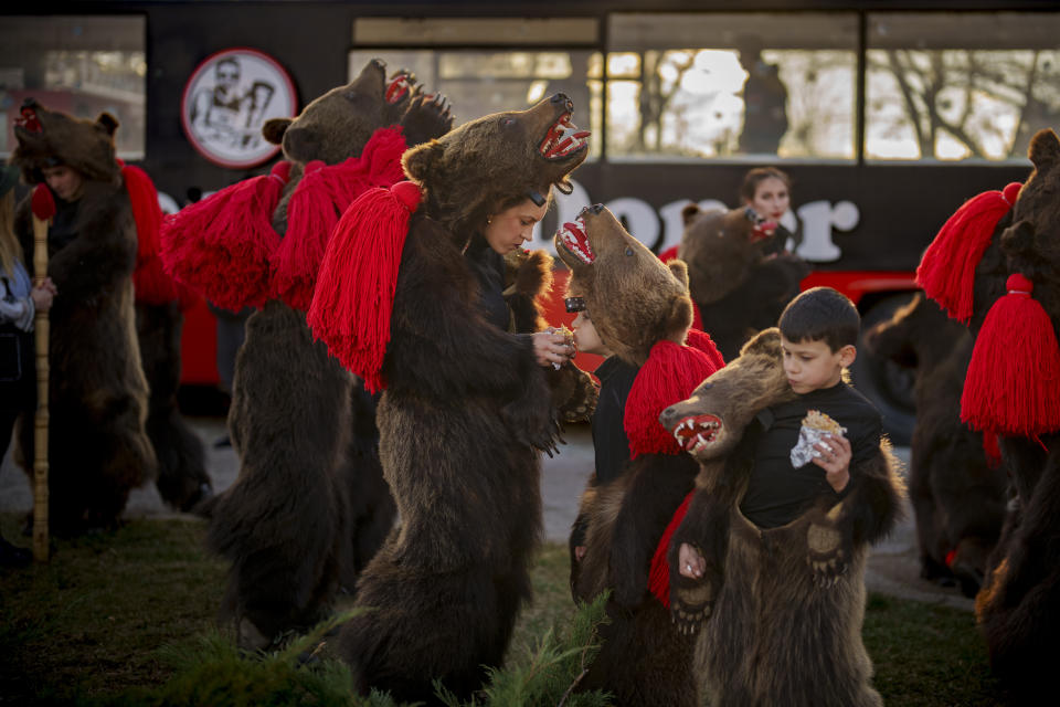 Miembros de un grupo tradicional de danza del oso comen antes de actuar en un festival en Moinesti, en el norte de Rumanía, el 27 de diciembre de 2023. Hace siglos, quienes vivían en lo que ahora es el noreste de Rumanía se cubrían con pieles de oso y bailaban para ahuyentar a los malos espíritus. Esa costumbre es conocida hoy en día como el Festival del Baile del Oso, que cada diciembre atrae a multitud de turistas. (AP Foto/Vadim Ghirda)
