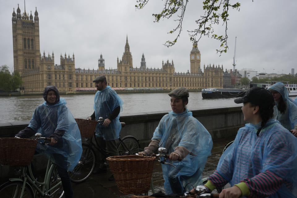 Tourists on a cycle tour in wet weather plastic macs, cycle past the Houses of Parliament, in London Friday, May 3, 2024. Britain's governing Conservative Party is suffering heavy losses as local election results pour in Friday, piling pressure on Prime Minister Rishi Sunak ahead of a U.K. general election in which the main opposition Labour Party appears increasingly likely to return to power after 14 years. (AP Photo/Kin Cheung)