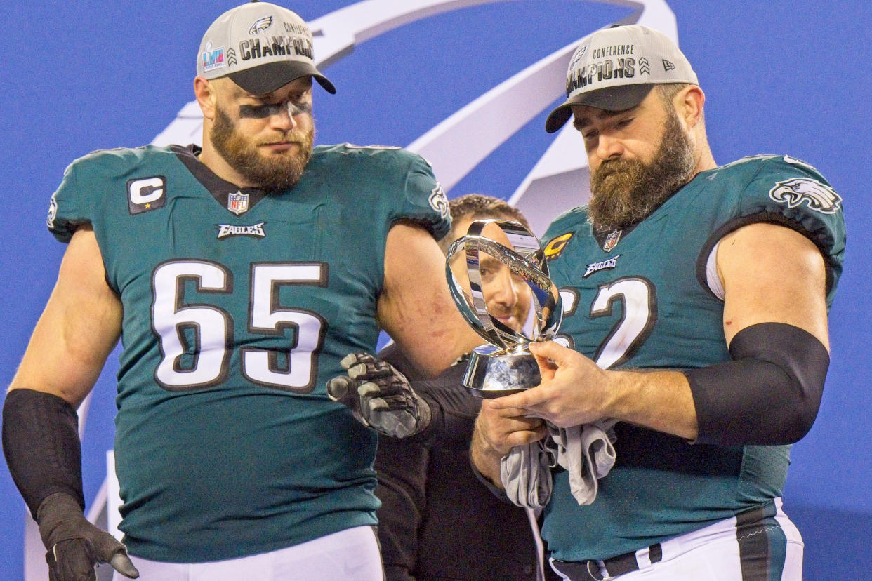 PHILADELPHIA, PA - JANUARY 29: Philadelphia Eagles General Manger Howie Roseman peaks thru the Championship trophy held by Philadelphia Eagles offensive tackle Lane Johnson (65) and Philadelphia Eagles center Jason Kelce (62) during the Championship game between the San Fransisco 49ers and the Philadelphia Eagles on January 29, 2023. (Photo by Andy Lewis/Icon Sportswire via Getty Images)