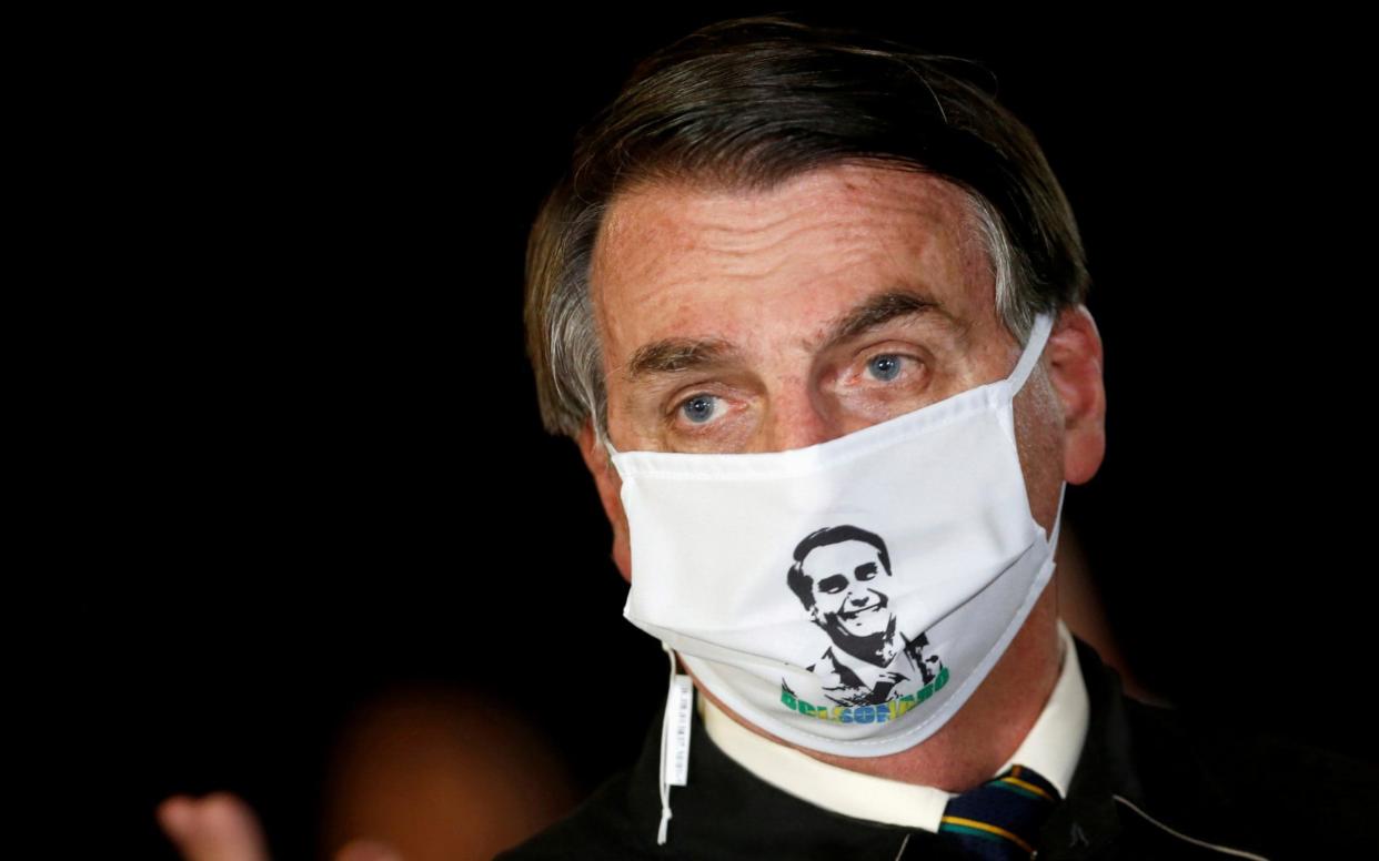Jair Bolsonaro wears a face mask as he talks to journalists in Brasilia -  Adriano Machado/Reuters