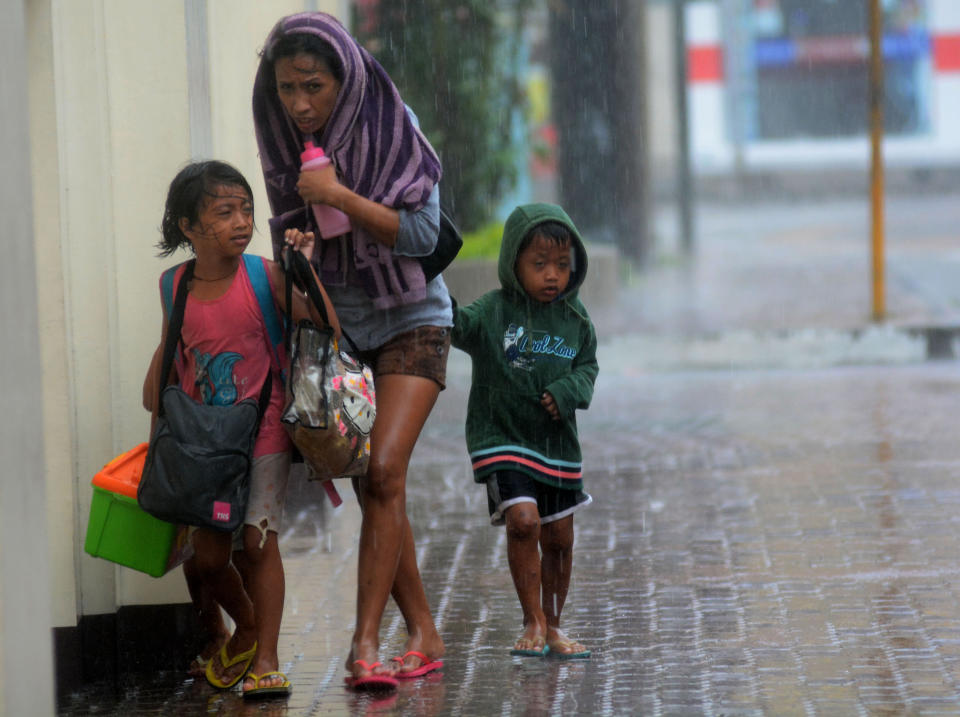 Una mujer y sus hijos se enfrentan, mientras se dirigen a un centro de evacuación, a las duras lluvias provocadas por el tifón Haiyan en el centro de Filipinas este 8 de noviembre 