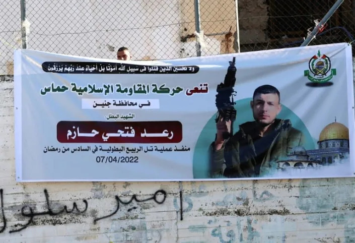 A poster of the 28-year-old Palestinian assailant from Jenin, Raad Hazem, who killed three Israeli civilians and wounded 12 at a Tel Aviv bar before he was shot dead, is displayed in Jenin in the occupied West Bank, on April 12, 2022 (AFP/JAAFAR ASHTIYEH)