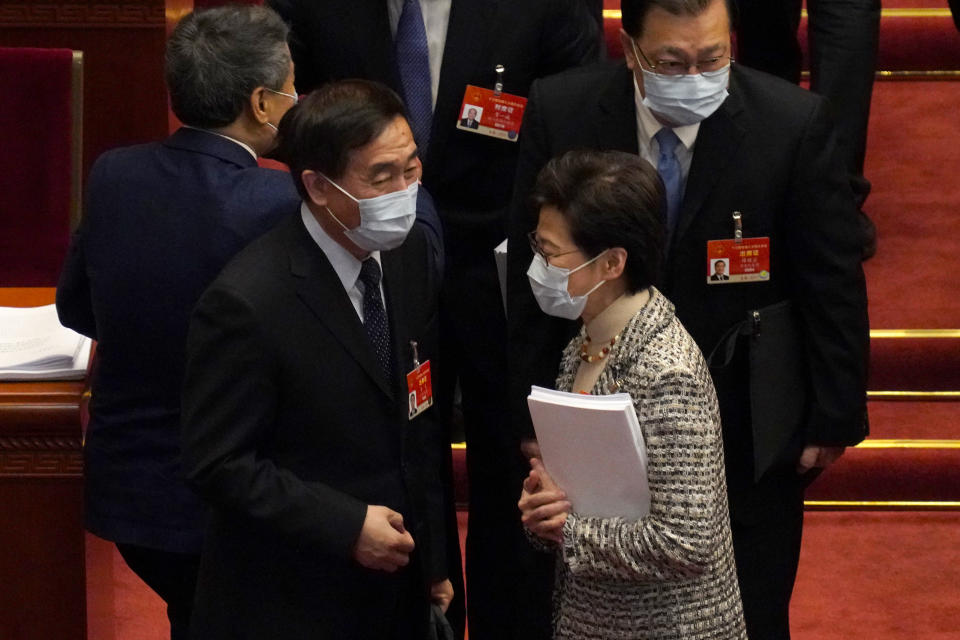 Hong Kong Chief Executive Carrie Lam, right, talks with fellow delegates after the opening session of China's National People's Congress (NPC) at the Great Hall of the People in Beijing, Friday, March 5, 2021. (AP Photo/Andy Wong)