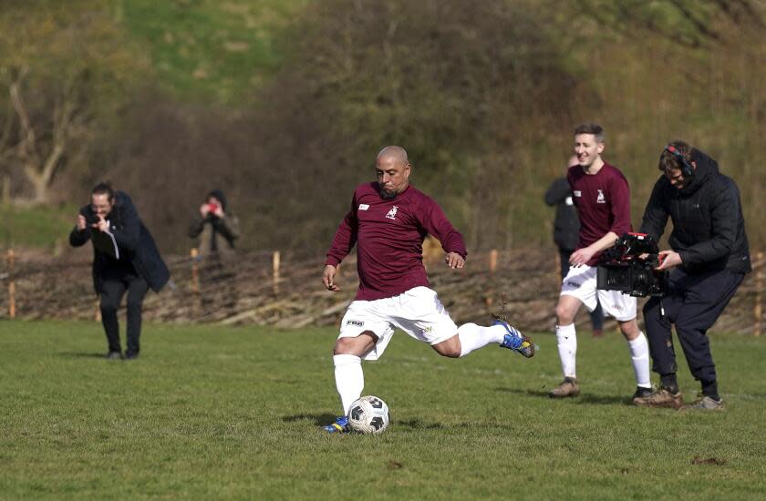 Brazil soccer player Roberto Carlos scores a penalty kick for Bull In The Barne United, during a match at the Hanwood Village Hall Recreation Centre, in Shrewsbury, England, Friday March 4, 2022, after the team won a raffle to have a soccer legend play on their team. Money raised from the raffle, goes towards Football Beyond Borders, a charity that helps disadvantaged young people in the community. (Nick Potts/PA via AP)