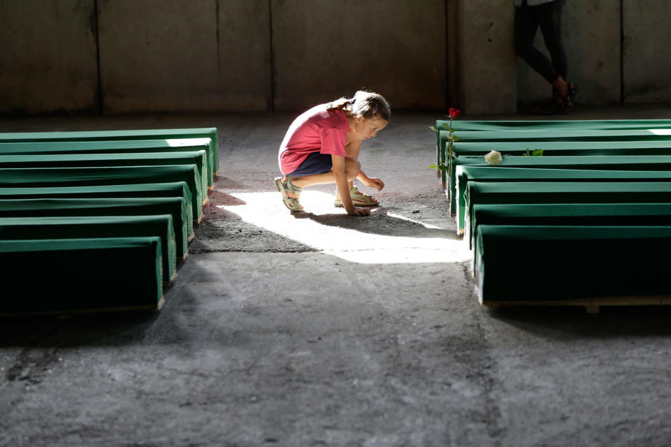 A girl reads a coffin name tag