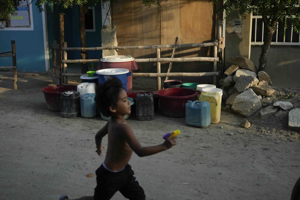 A boy runs past containers lined up in front of a house, waiting to be filled from a water truck in the Los Polvorines area of Piura, Peru Thursday, Feb. 29, 2024. Peru declared a health emergency in most of its provinces on Feb. 26 due to a growing number of dengue cases. (AP Photo/Martin Mejia)