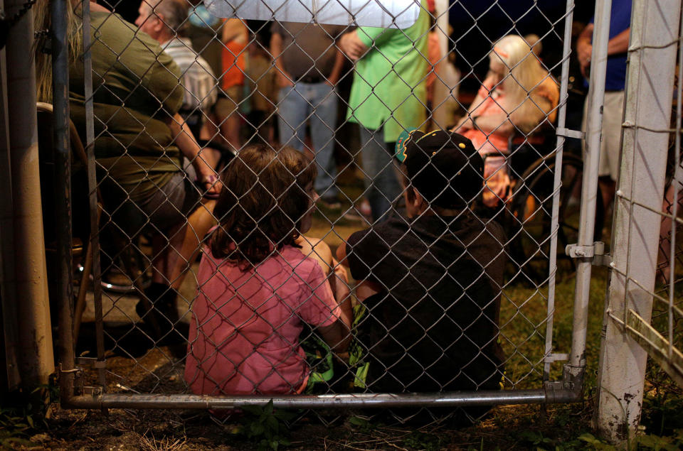 Children sit against a fence