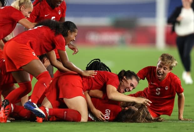 Canadian players celebrate their gold-medal win over Sweden on Friday, Aug. 6 in Tokyo. But the team has yet to find a similar triumph at the World Cup.  (Francois Nel/Getty Images - image credit)