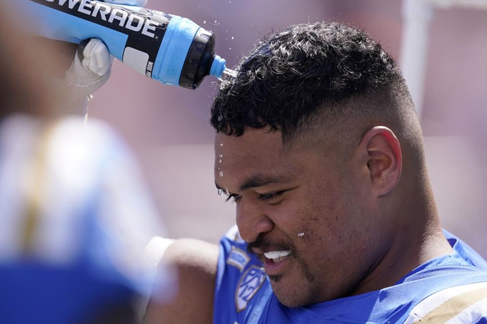 UCLA offensive lineman Atonio Mafi sprays water on his head.