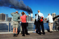 <p>Pedestrians on the waterfront in Brooklyn, New York, look across the East River to the burning World Trade Center towers Sept. 11, 2001 after a terrorist attack. (Photo: Henny Ray Abrams/AFP/Getty Images) </p>