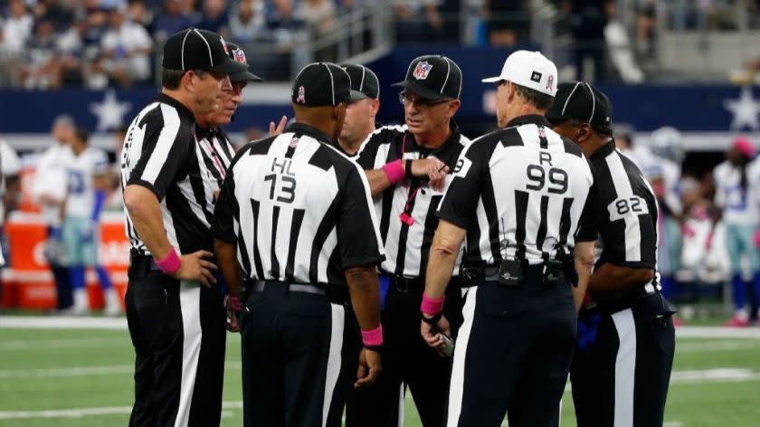 Head linesman Patrick Turner (13), referee Tony Corrente (99), field judge Buddy Horton (82) and other officials gather on the field during a game between the Bengals and the Cowboys on Oct. 9.