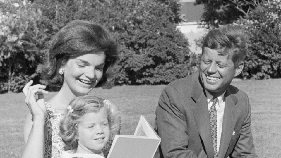 Senator John F. Kennedy (right) is shown with his family in the backyard of his summer home here July 21st. His wife, Jacqueline, holds Caroline, 2.