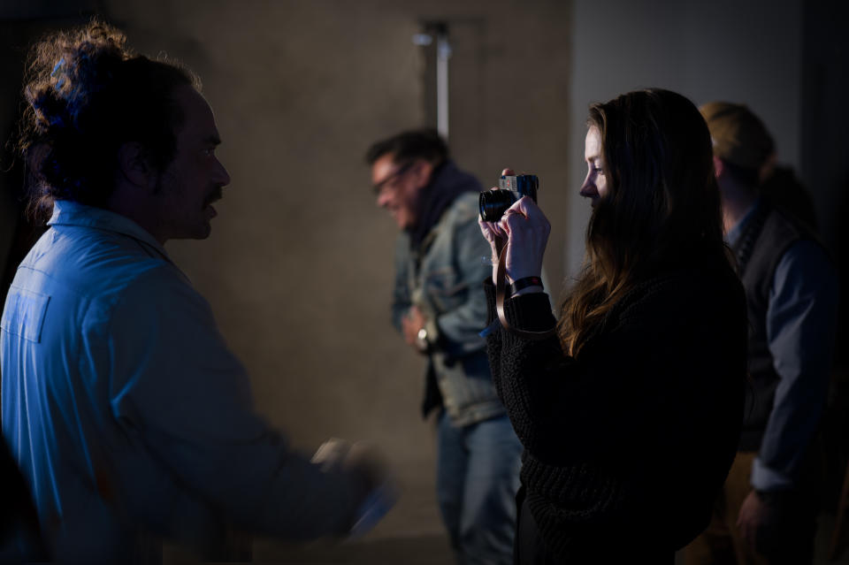 Young photographer taking a picture of their subject using the rear screen of the camera of