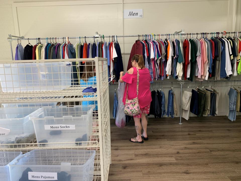 A mother and her daughter shop for free clothing for a loved one at Love and Care Ministries on March 13, 2024, amidst empty boxes in the men's section in need of donations.