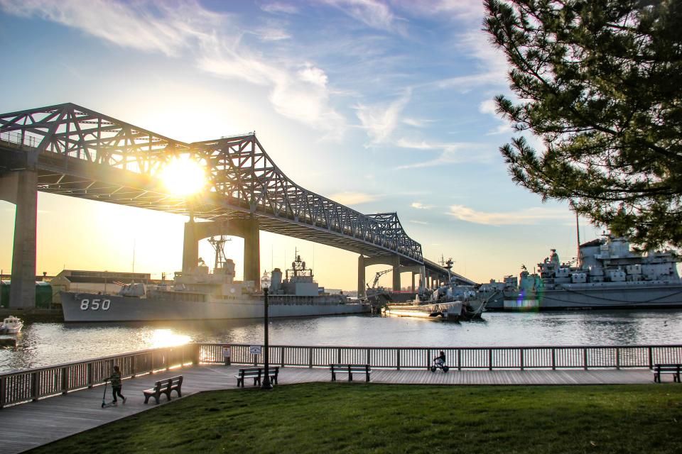 The sun begins to set behind the Braga Bridge and Battleship Cove in Fall River. Battleship Cove Executive Director Megan Rathbun said her organization may apply for a Mass Humanities grant to host a program on Frederick Douglass next funding cycle.