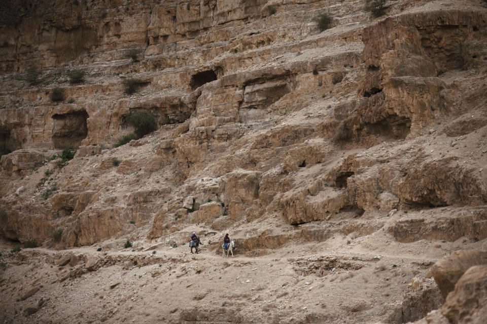 FILE - In this Jan. 16, 2012 file photo Palestinian boys ride donkeys near St. George Monastery in Judean desert. St. George is a 5th century Byzantine monastery built at the site of the cave where according to Christian faith Elijah the Prophet hid from Jezebel. Located between Jerusalem and Jericho, the Judean Desert provided an inspiration to thousands of hermits who lived here in the early Middle Ages. With its breathtaking, rugged beauty, it was the perfect setting for those searching spiritual fullness in the emptiness of the desert. Today only a handful of monks live here, but the Judean Desert and its stunning monasteries continue to attract thousands of visitors from all over the world. (AP Photo/Dusan Vranic, Files)