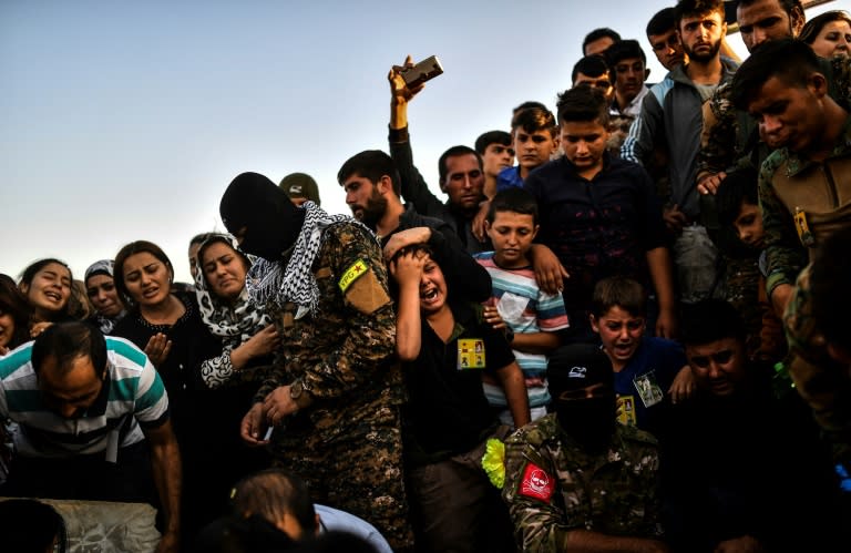 A picture taken on October 14, 2017 in the Kurdish town of Kobane in northern Syria shows people mourning during the funeral of a Kurdish fighter, who was killed in clashes against Islamic State (IS) group fighters in the city of Deir Ezzor