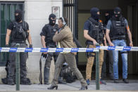 FILE - In this June 9, 2016 file photo, a woman walks by special police officers guarding the entrance of the federal court building in Brussels. One year after the March 22, 2016 Brussels attacks, the city's physical scars may have healed, but the pain is still apparent beneath the surface. (AP Photo/Olivier Matthys, File)