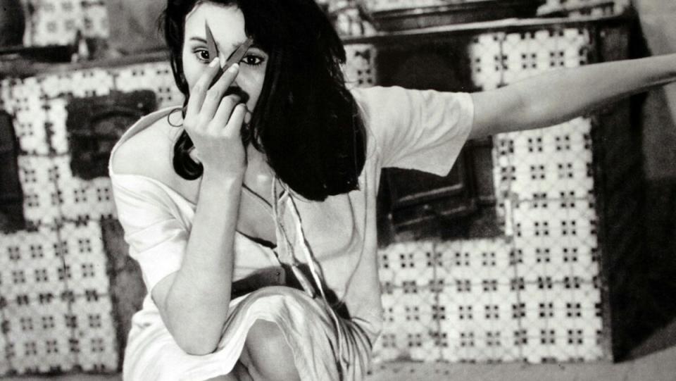 Dahlia Lavi holds a pair of scissors up to her face in the Italian folk horror film Il Demonio.