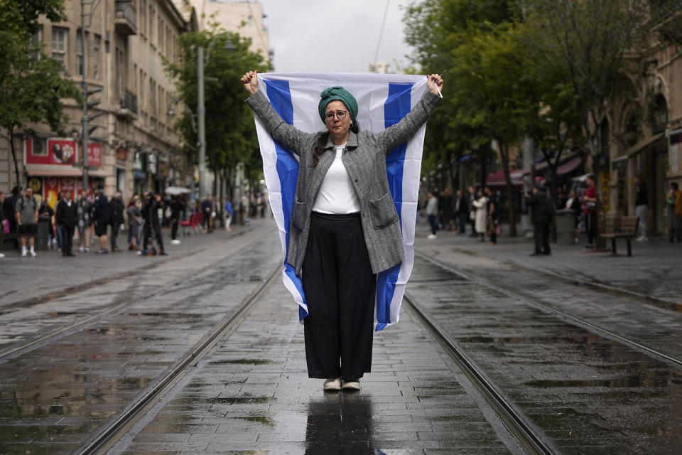A woman stands still with an Israeli flag during a two-minute siren in memory of victims of the Holocaust, in Jerusalem, Monday, May 6, 2024. (AP Photo/Ohad Zwigenberg)