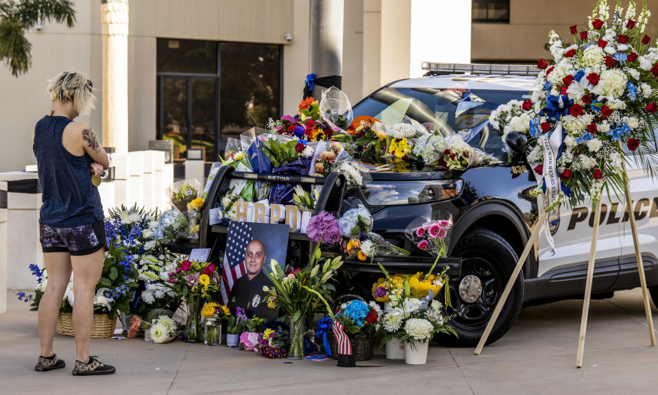 After placing flowers, Marriah Blackmore, 26, of Huntington Beach, who works in law enforcement in Riverside, pauses for a moment at the memorial setup for Huntington Beach police officer Nicholas Vella outside the Huntington Beach Police Department in Huntington Beach, Calif., Sunday, Feb. 20, 2022. Officer Vella, 44, a 14-year veteran of the Huntington Beach Police Department was killed on Saturday in a helicopter crash during an investigation in Newport Beach. A second officer was hospitalized with critical injuries. (Leonard Ortiz/The Orange County Register via AP)