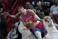 Washington Wizards center Kristaps Porzingis (6) drives to the basket against Miami Heat center Bam Adebayo, rear, and guard Kyle Lowry, right, during the first half of an NBA basketball game, Friday, Nov. 25, 2022, in Miami. (AP Photo/Wilfredo Lee)