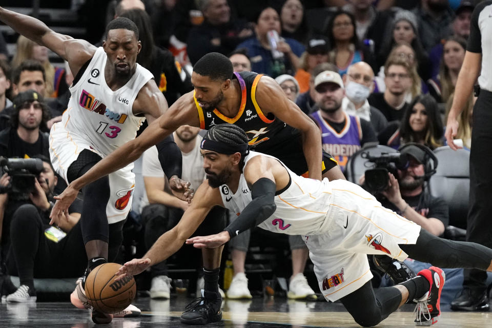 Miami Heat guard Gabe Vincent (2) dives for the ball against Phoenix Suns forward Mikal Bridges, top right, as Heat center Bam Adebayo (13) moves to it during the first half of an NBA basketball game in Phoenix, Friday, Jan. 6, 2023. (AP Photo/Ross D. Franklin)