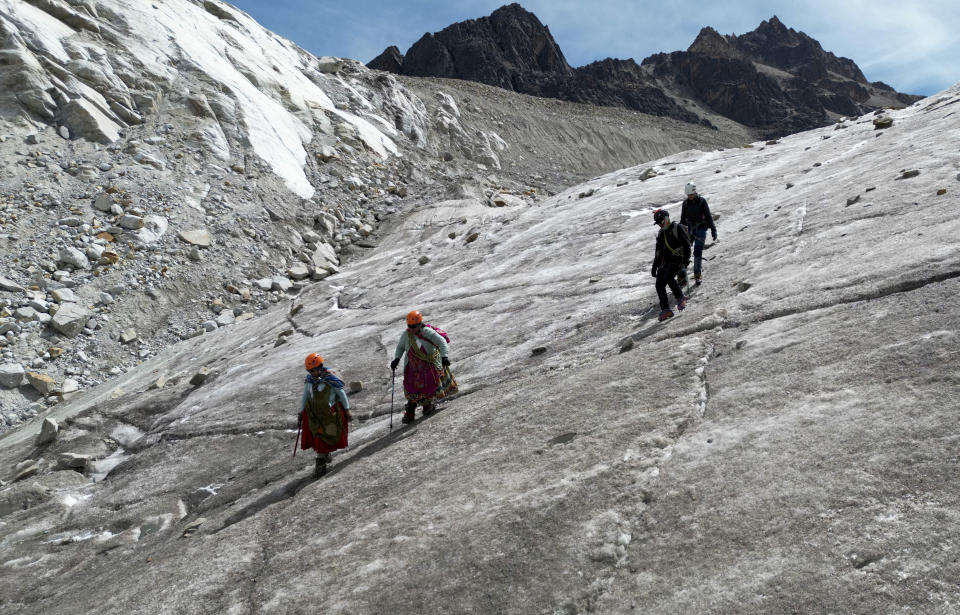 Cholita climbers Suibel Gonzales, left, and her mother Lidia Huayllas, descend with tourists from the Huayna Potosi glacier, near El Alto, Bolivia, Sunday, Nov. 5, 2023. In the last 30 years Bolivian glaciers have lost 40% of their ice thickness due to climate change, according to Edson Ramírez, a glaciologist from the Pierre and Marie Curie University in France. (AP Photo/Juan Karita)