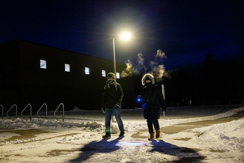 AMES, IOWA - JANUARY 15, 2024: Condensation forms as Natalia Porter, right, of Huntington Beach and her son-in-law Jonathan Stoner breath the sub-zero air on a snowy path to Caucuses night at Mitchell Elementary School on January 15, 2024 in Ames, Iowa. Porter is going to observe the process while Stoner, originally from Lakewood, California and now living in Ames, Iowa will be voting. (Gina Ferazzi / Los Angeles Times)