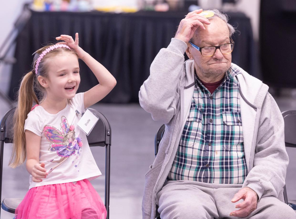 Brielle Hall, 5, and Don Hamilton place the letter H on their heads during an Artful Living and Learning intergenerational class at the Massillon Museum earlier this month.