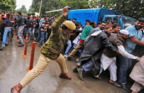 <p>An Indian police officer disperses demonstrators in Srinagar during a protest by government employees demanding back wages and conversion of temporary jobs to permanent ones, on May 24, 2016. (Danish Ismail/Reuters) </p>