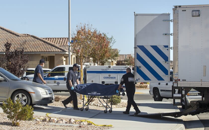 Lancaster, CA - November 29, 2021: A body is loaded onto a coroner's truck in front of a home on Garnet Lane in Lancaster where a woman and four children were shot and killed last night. (Mel Melcon / Los Angeles Times)