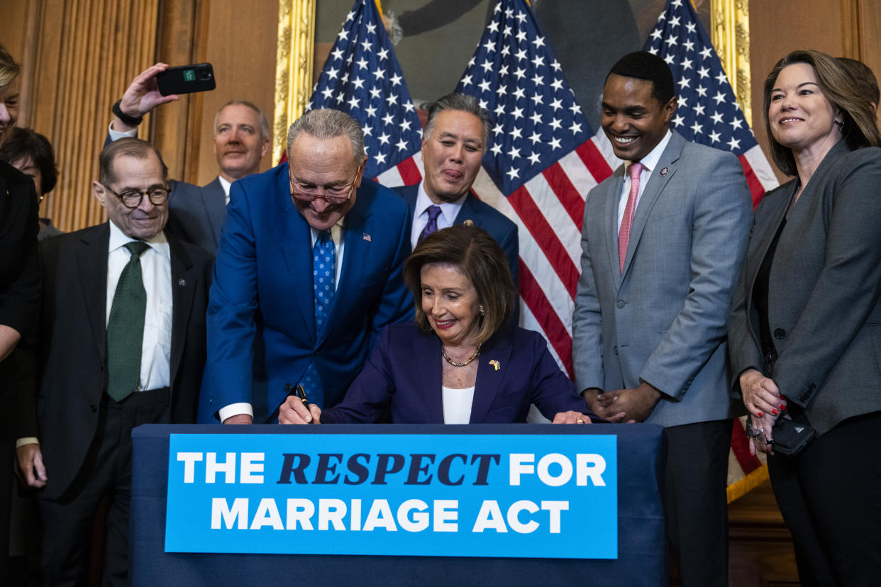 House Speaker Nancy Pelosi and Senate Majority Leader Chuck Schumer, with other lawmakers, all smiling broadly, after the House passed the Respect for Marriage Act.