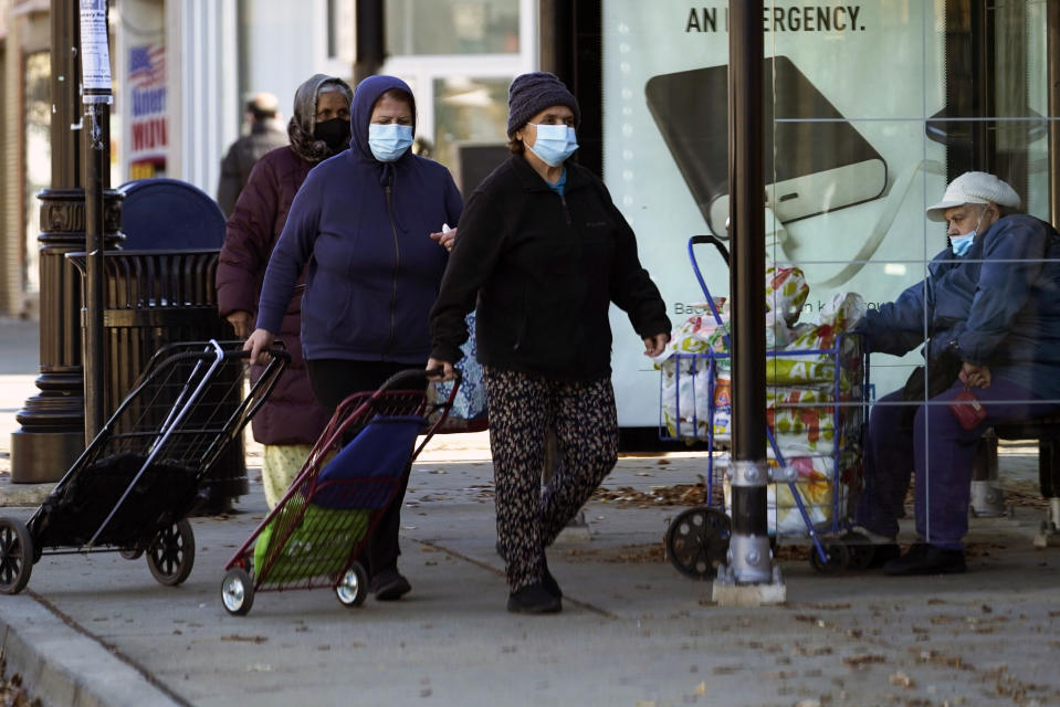 FILE - In this Nov. 12, 2020, file photo, people wear a face masks as they walk to an ICNA (Islamic Circle of North America) Relief Resource Center and Food Pantry during the COVID-19 pandemic in Chicago. In states like New Mexico and Washington and cities such as Philadelphia to Chicago, leaders are ordering or imploring residents to stay home to help stem a rising tide of infections that threatens to overwhelm the health care system. (AP Photo/Nam Y. Huh, File)
