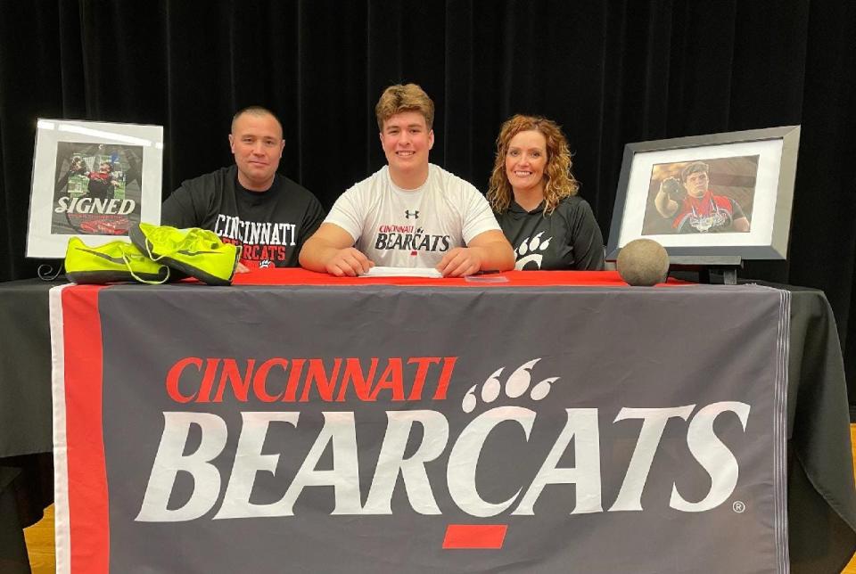Tyler Thompson smiles with his parents after signing his letter of intent to the University of Cincinnati.