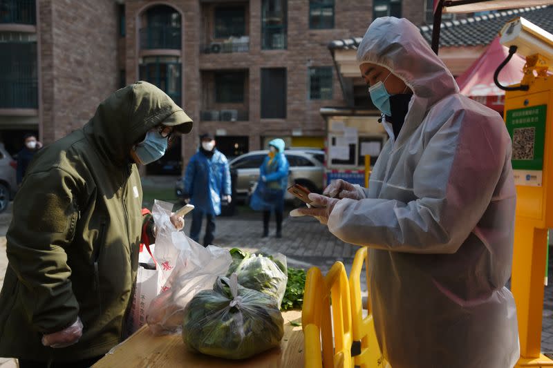 Resident collects vegetables purchased through group orders at the entrance of a residential compound in Wuhan