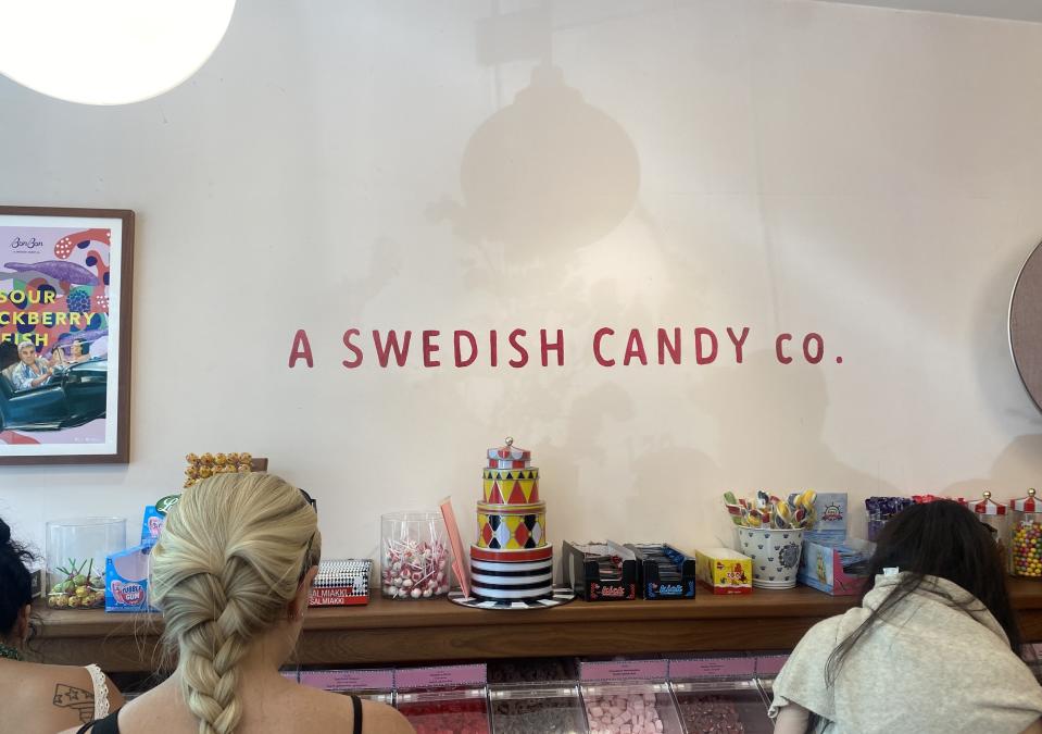 People at a counter with various candies in jars and a decorative candy cake centerpiece at A Swedish Candy Co