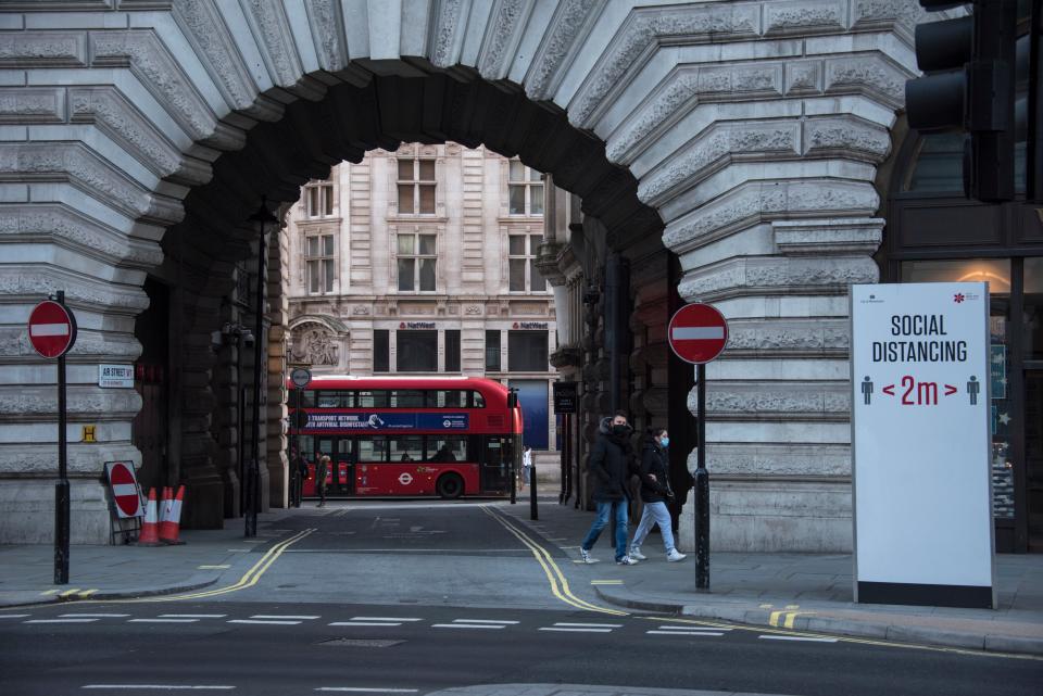 People wear face masks as they walk past a social distancing sign in Regent Street (AP)