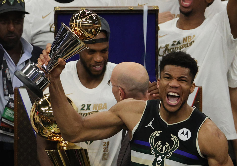 Giannis Antetokounmpo holds up the NBA Finals MVP trophy with a huge smile on his face. Pure joy emanates from him.