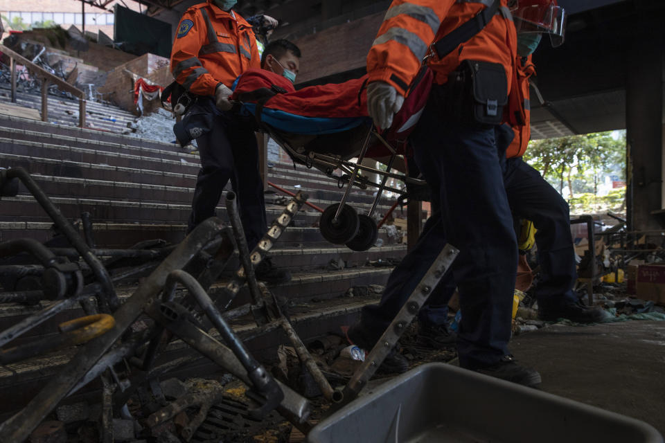 A man is evacuated by medics past charred debris from the Polytechnic University in Hong Kong on Wednesday, Nov. 20, 2019. Hong Kong schools have reopened after a six-day shutdown but students were facing transit disruptions as the last protesters remained holed up on a university campus. (AP Photo/Ng Han Guan)