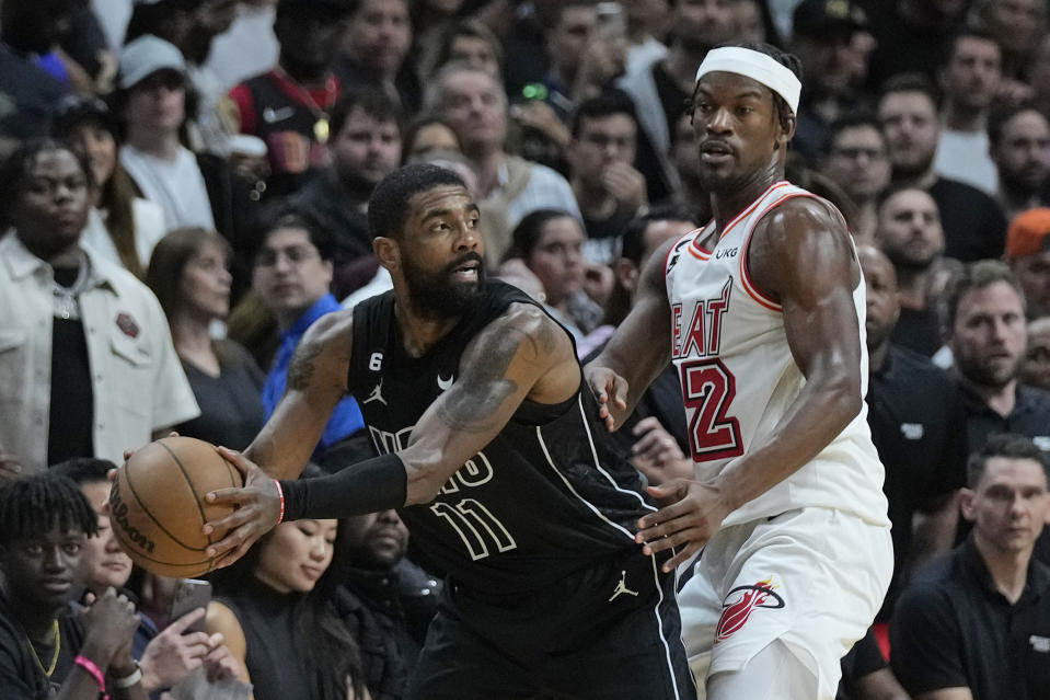 Brooklyn Nets guard Kyrie Irving (11) looks for an open teammate past Miami Heat forward Jimmy Butler (22) during the second half of an NBA basketball game, Sunday, Jan. 8, 2023, in Miami. (AP Photo/Wilfredo Lee)