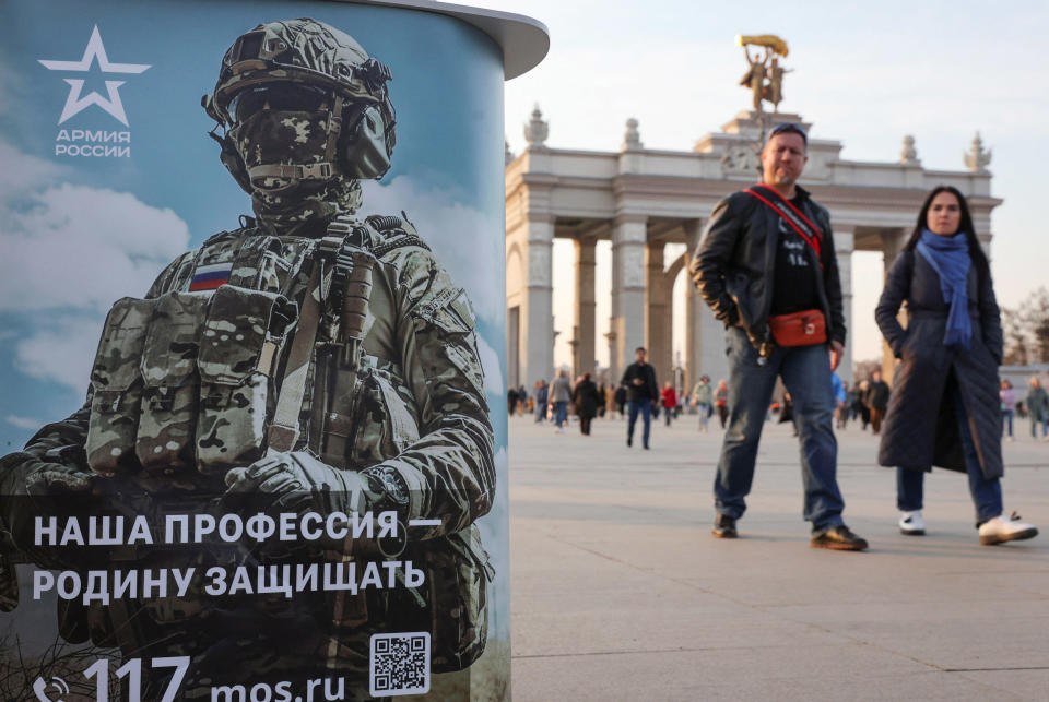 People walk past a desk promoting Russian army service in Moscow, Russia April 12, 2023.   (Yulia Morozova / Reuters via Alamy Stock Photo)