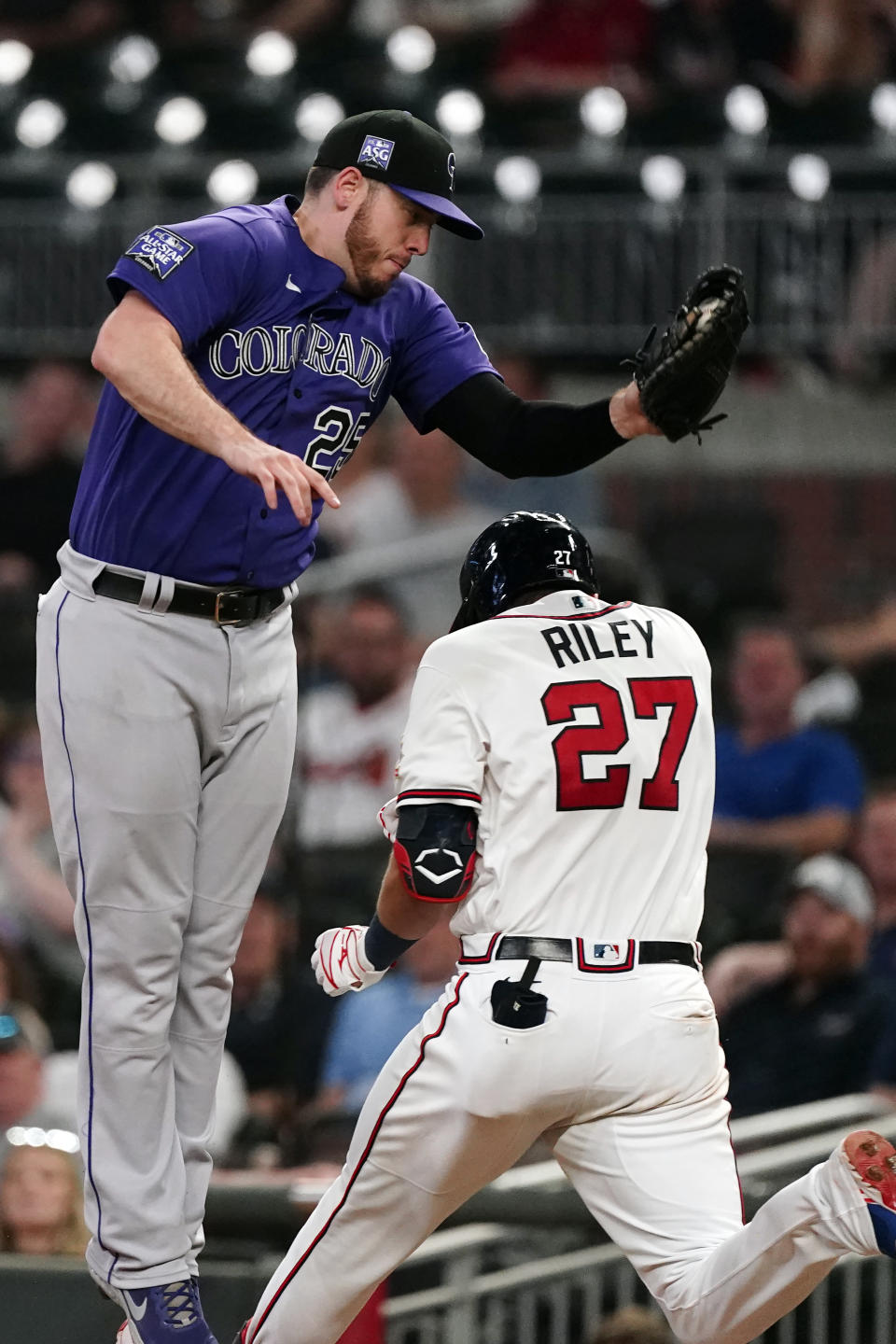 Atlanta Braves' Austin Riley (27) is safe at first base as Colorado Rockies first baseman C.J. Cron (25) handles the wild throw from shortstop Trevor Story in the sixth inning of a baseball game Tuesday, Sept. 14, 2021, in Atlanta. (AP Photo/John Bazemore)