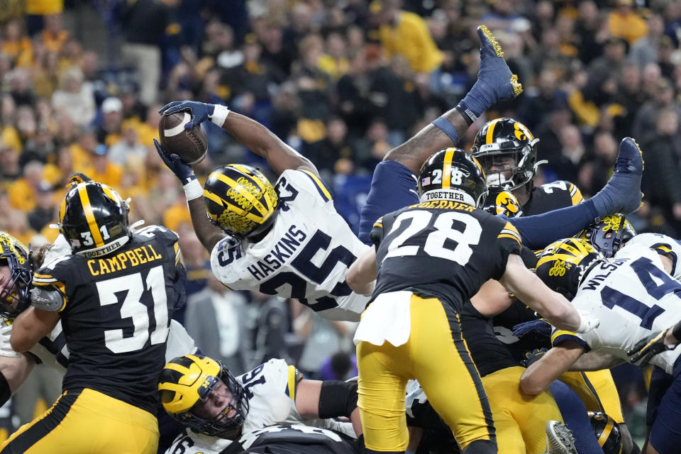 Michigan running back Hassan Haskins (25) scores on a 1-yard touchdown run ahead of Iowa linebacker Jack Campbell (31) during the second half of the Big Ten championship NCAA college football game, Saturday, Dec. 4, 2021, in Indianapolis. (AP Photo/AJ Mast)