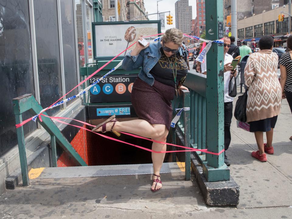 A woman steps over red tape blocking a subway entrance in New York City.