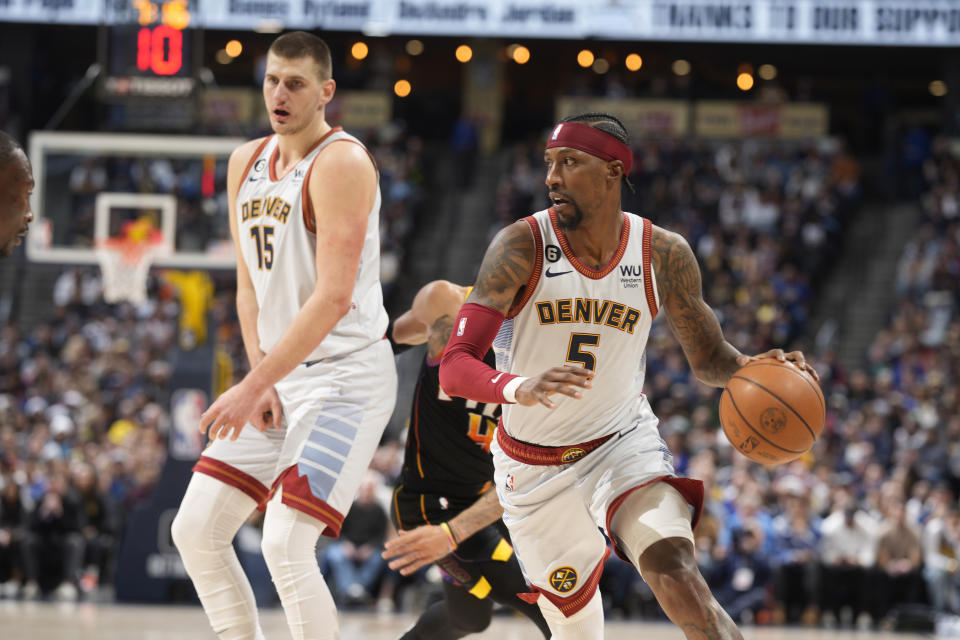 Denver Nuggets guard Kentavious Caldwell-Pope, front right, slips past Phoenix Suns guard Duane Washington Jr., back right, as he is slowed by Nuggets center Nikola Jokic in the first half of an NBA basketball game Wednesday, Jan. 11, 2023, in Denver. (AP Photo/David Zalubowski)