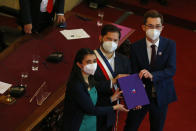 Chilean President Gabriel Boric, center, holds the final draft of a proposed, new constitution for the country alongside members of the Constitutional Convention, Maria Elisa Quinteros and Gaspar Dominguez, in Santiago, Chile, Monday, July 4, 2022. Chileans elected an assembly to write fresh governing principles and put them to a national vote in 2022 with the goal of a more inclusive country and the erasure of a relic of military rule. (AP Photo/Luis Hidalgo)