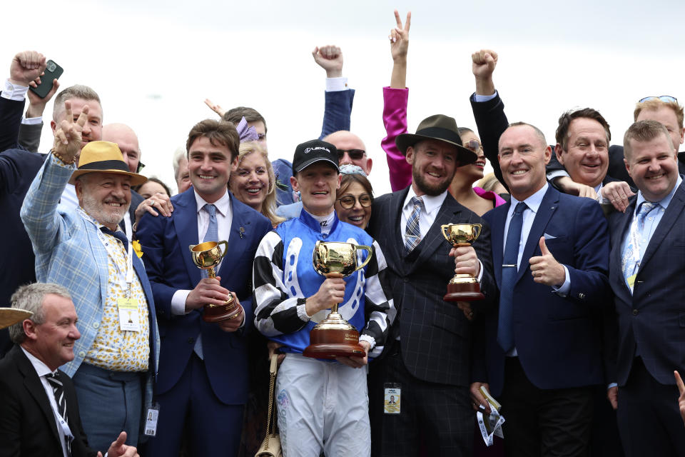 Jockey Mark Zahra, center, holds his trophy as he celebrates with connections after winning the Melbourne Cup horse race on Gold Trip in Melbourne, Australia, Tuesday, Nov. 1, 2022. (AP Photo/Asanka Brendon Ratnayake)