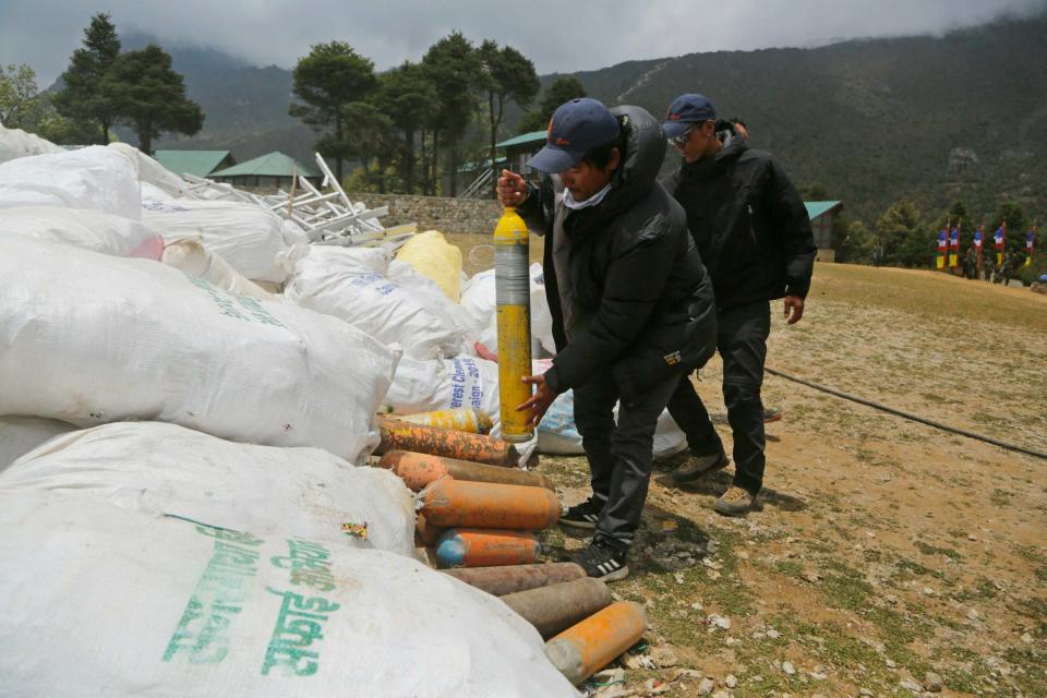 Members of a clean-up operation this spring pile up empty oxygen cylinders collected from the mountain (AP)